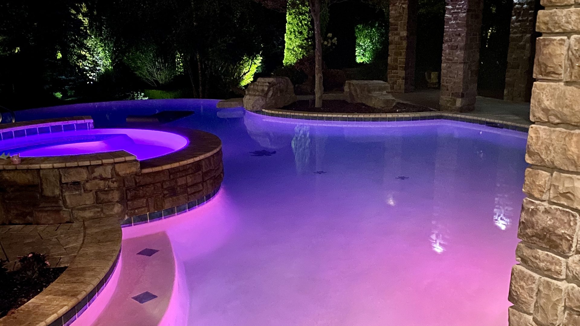 Custom gunite pool with LED lighting and spillover spa at night